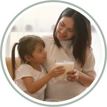 A woman is holding a glass of milk next to a little girl.